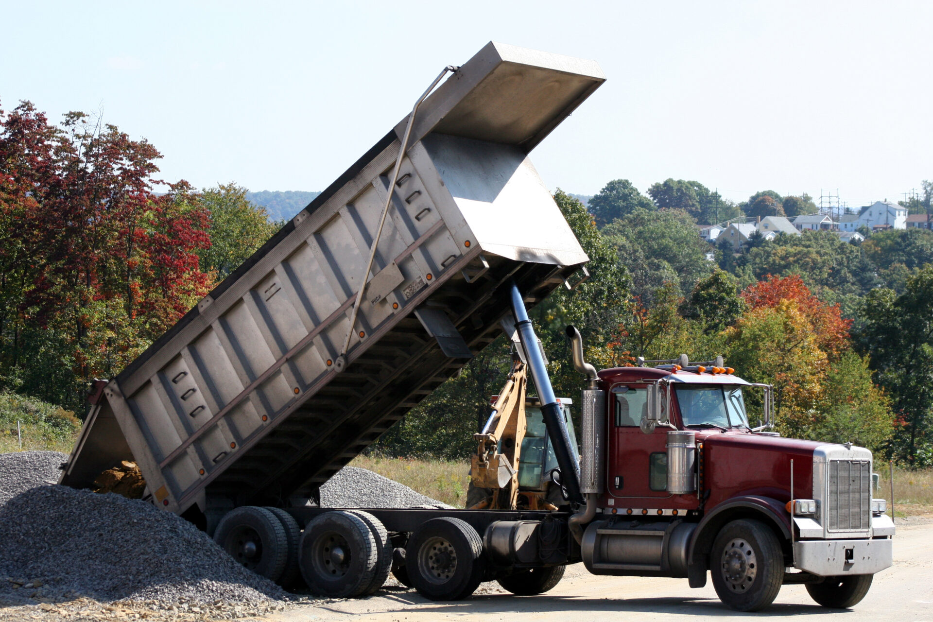 Dump Truck dumping dirt at residential construction site.